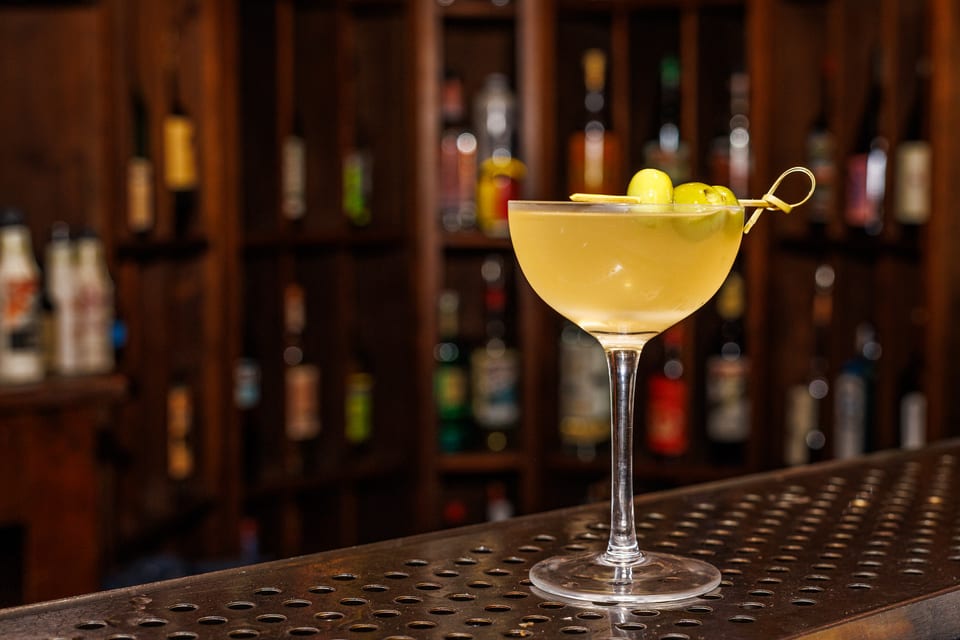 Classic martini with olives, evening bar lighting