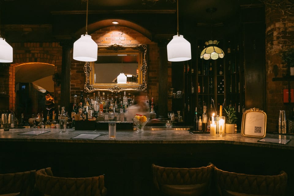 The Alexander bar at evening — brass pendant lights, leather seats, warm tungsten light