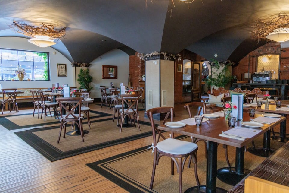 The Alexander dining room — vaulted brick ceilings, set tables with linen, and warm chandelier light