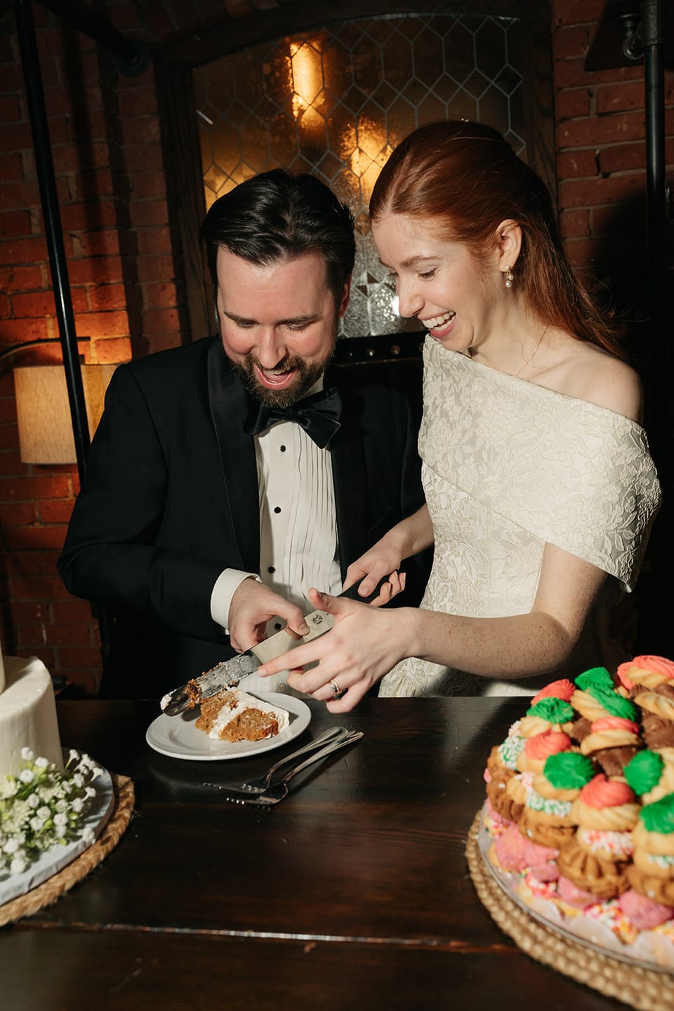 Newlyweds cutting their wedding cake with Italian cookie tray in foreground
